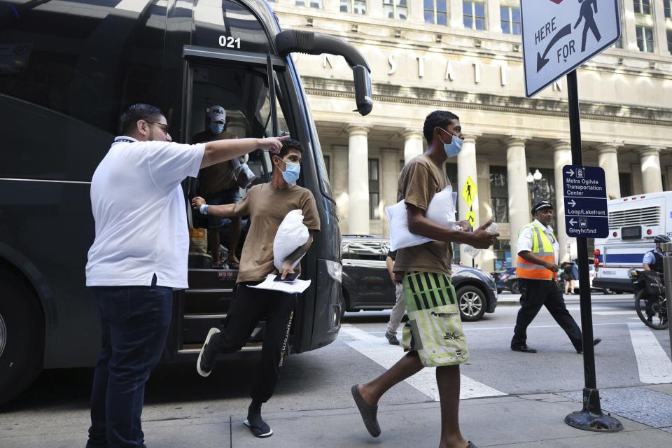 people getting off a black bus in the city, a person in a white shirt pointing them where to go