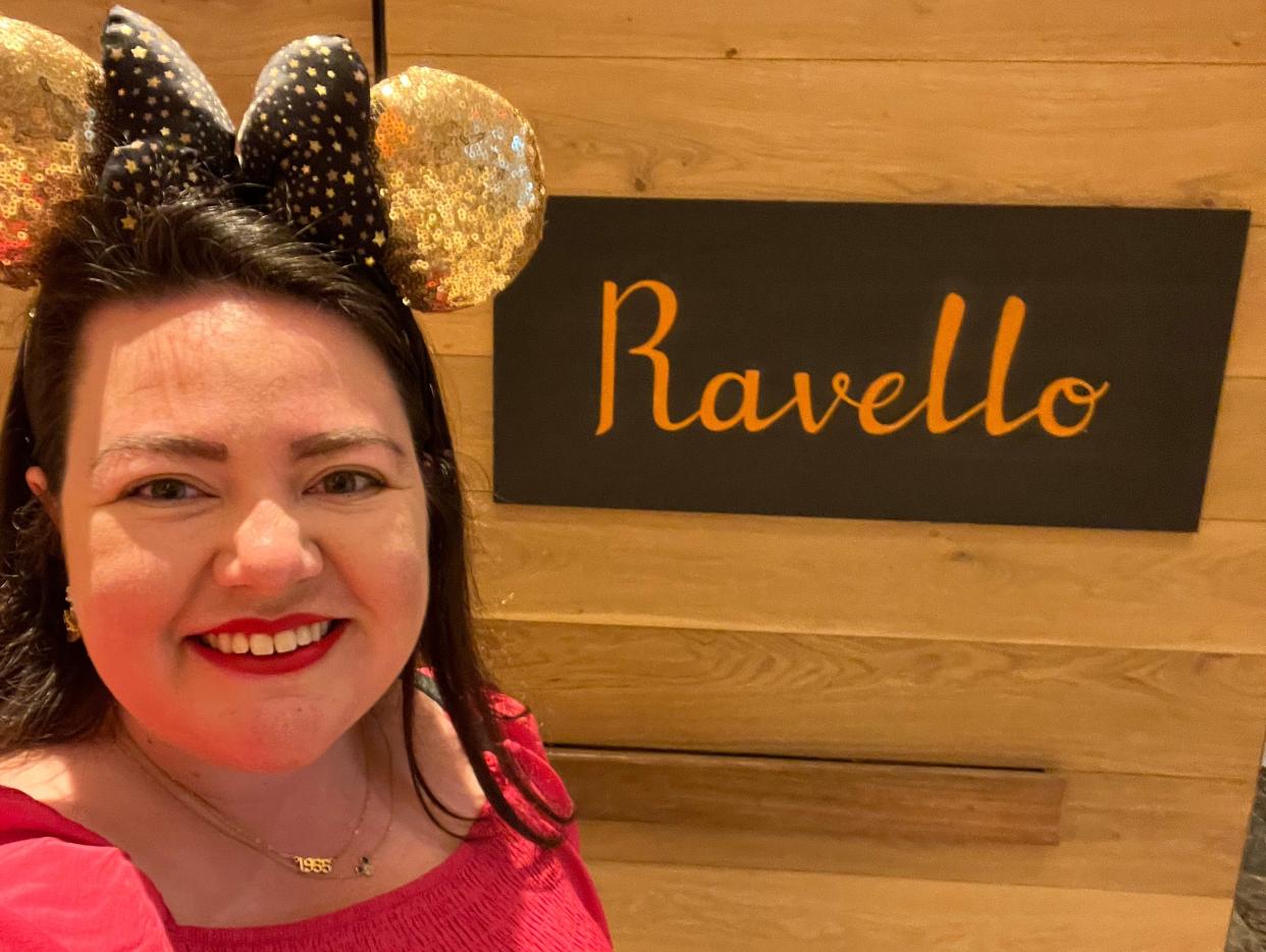 megan posing with the ravello sign at the restaurant in the four seasons resort at disney world