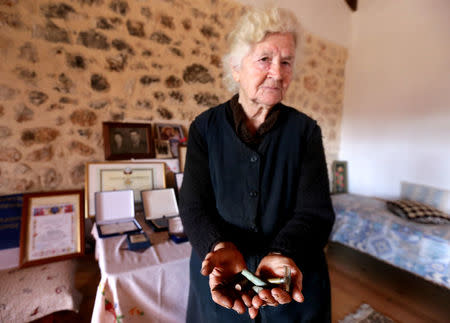 Ermioni Brigo, 85, holds bullets, empty shells and an old razor thought to belong to Greek World War Two soldiers in Himara, Albania January 26, 2018. Picture taken January 26, 2018. REUTERS/Florion Goga