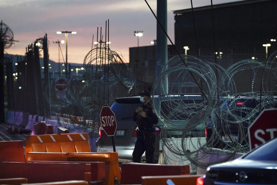 A Customs and Border Protection officer stands at the entrance to the San Ysidro Port of Entry Wednesday, March 2, 2022, seen from Tijuana, Mexico. More than 8,600 Russians have sought refuge in the U.S. on the Mexican border in recent months. To claim asylum in the U.S., they reach a tiny piece of U.S. soil before inspection booths. They must outsmart U.S. officers who try to block their path. (AP Photo/Gregory Bull)