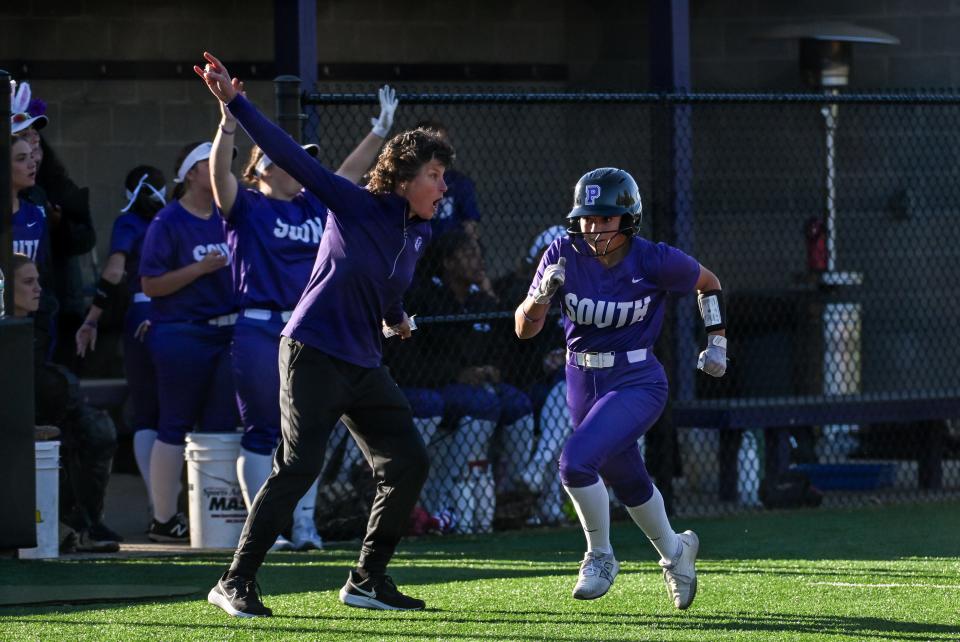 Bloomington South head coach Meg Montgomery (left) waves Carly Reed homeward in the fifth inning of their softball game against Bloomington North at South on Wednesday, April 24, 2024.