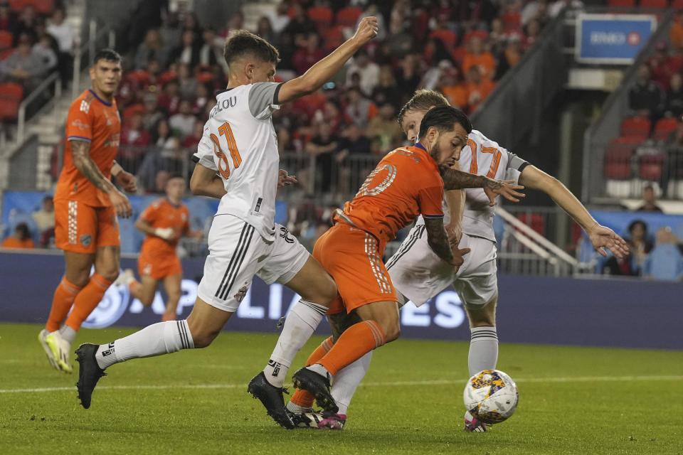 FC Cincinnati's Luciano Acosta bursts through the challenges of Toronto FC's Sigurd Rosted and Themi Antonoglou, right, during the first half of an MLS soccer match Saturday, Sept. 30, 2023, in Toronto. (Chris Young/The Canadian Press via AP)