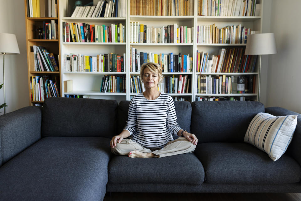 Woman meditating on couch to learn how to stop worrying about things you can't control