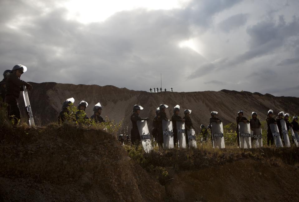 Riot police stand guard at an illegal mining operation in Huepetuhe district in Peru's Madre de Dios region in Peru, Monday, April 28, 2014. Some 1,500 soldiers, police and marines have begun destroying illegal gold mining machinery in Peru’s southeastern jungle region of Madre de Dios. Authorities began enforcing a ban on illegal mining Monday in the Huepetuhe district. They had given the state’s thousands of illegal miners until April 19 to get legal or halt operations. (AP Photo/Rodrigo Abd)