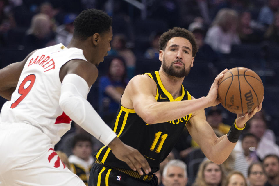 Golden State Warriors guard Klay Thompson (11) looks to shoot over Toronto Raptors forward RJ Barrett (9) during the first quarter of an NBA basketball game, Sunday, Jan. 7, 2024, in San Francisco. (AP Photo/D. Ross Cameron)