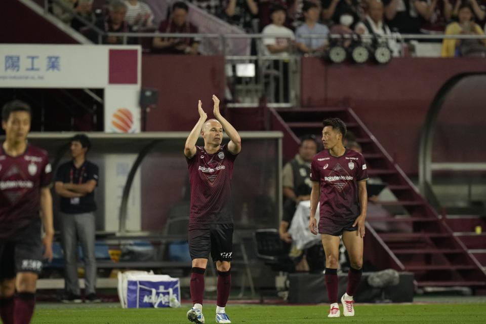 Vissel Kobe midfielder Andres Iniesta, center, reacts to audience members as he was changed and got off the pitch during the second half of a friendly soccer match against Consadole Sapporo in Kobe, Japan, Saturday, July 1, 2023. The 39-year-old Spanish footballer plays his last match for the Japanese club Saturday. (AP Photo/Hiro Komae)