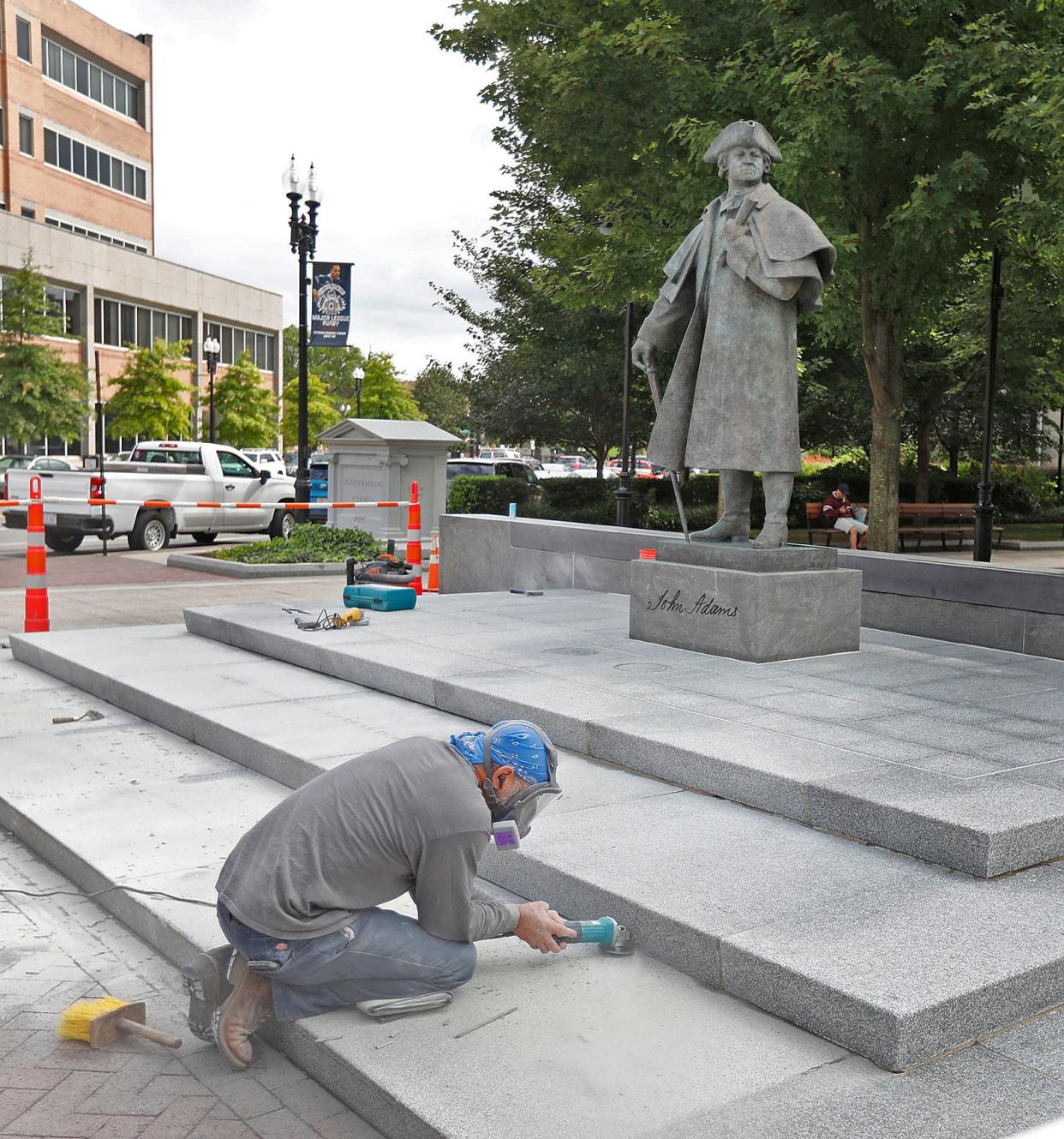 A stonemason works to re-point the granite base for the John Adams statue on the Hancock-Adams Common in Quincy Square on Wednesday, Sept. 21, 2022.