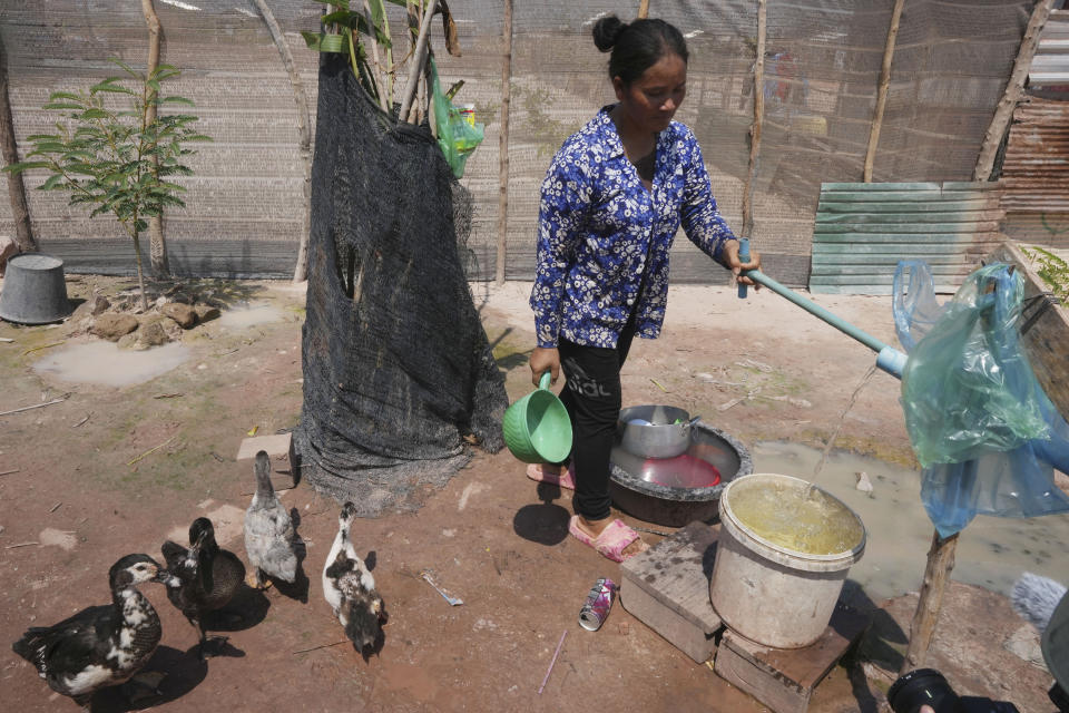 Chhem Hay, 37, pumps water behind her home at Run Ta Ek village in Siem Reap province, Cambodia, on April 2, 2024. She decided last June to take the opportunity to move from the village where she'd lived since she was a young teenager to the new settlement. Cambodia's program to relocate people living on the famous Angkor archaeological site is drawing international concern over possible human rights abuses, while authorities maintain they're doing nothing more than protecting the UNESCO World Heritage Site from illegal squatters. (AP Photo/Heng Sinith)