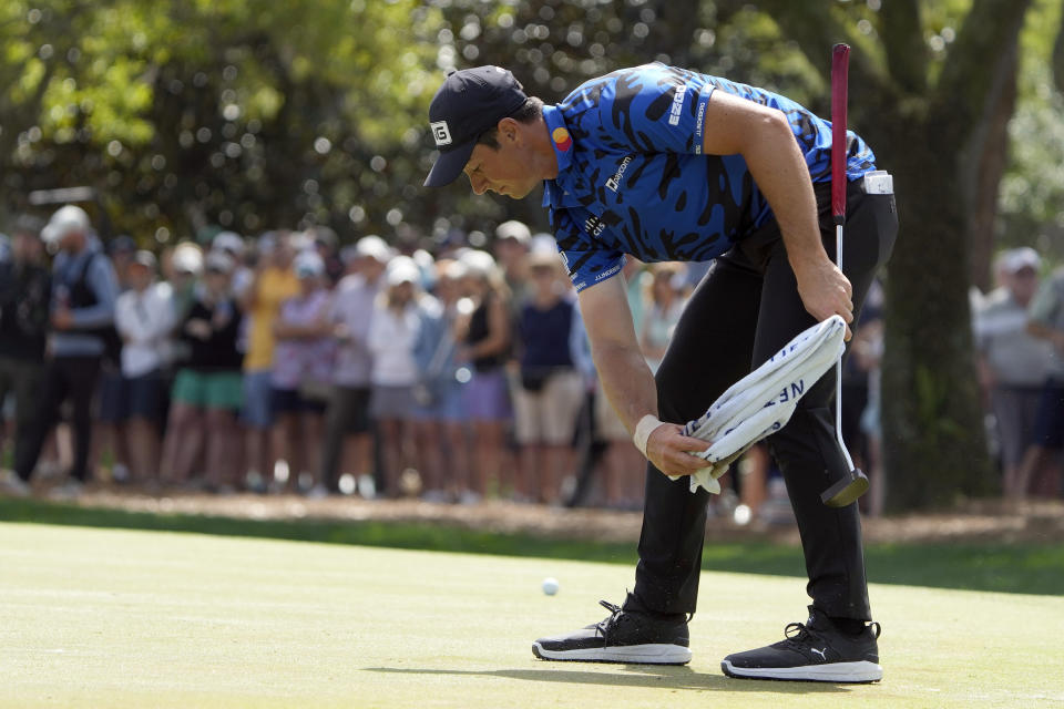 Viktor Hovland, of Norway, brushes sand off the ninth green after hitting from the sand during the first round of The Players Championship golf tournament Thursday, March 14, 2024, in Ponte Vedra Beach, Fla. (AP Photo/Lynne Sladky)