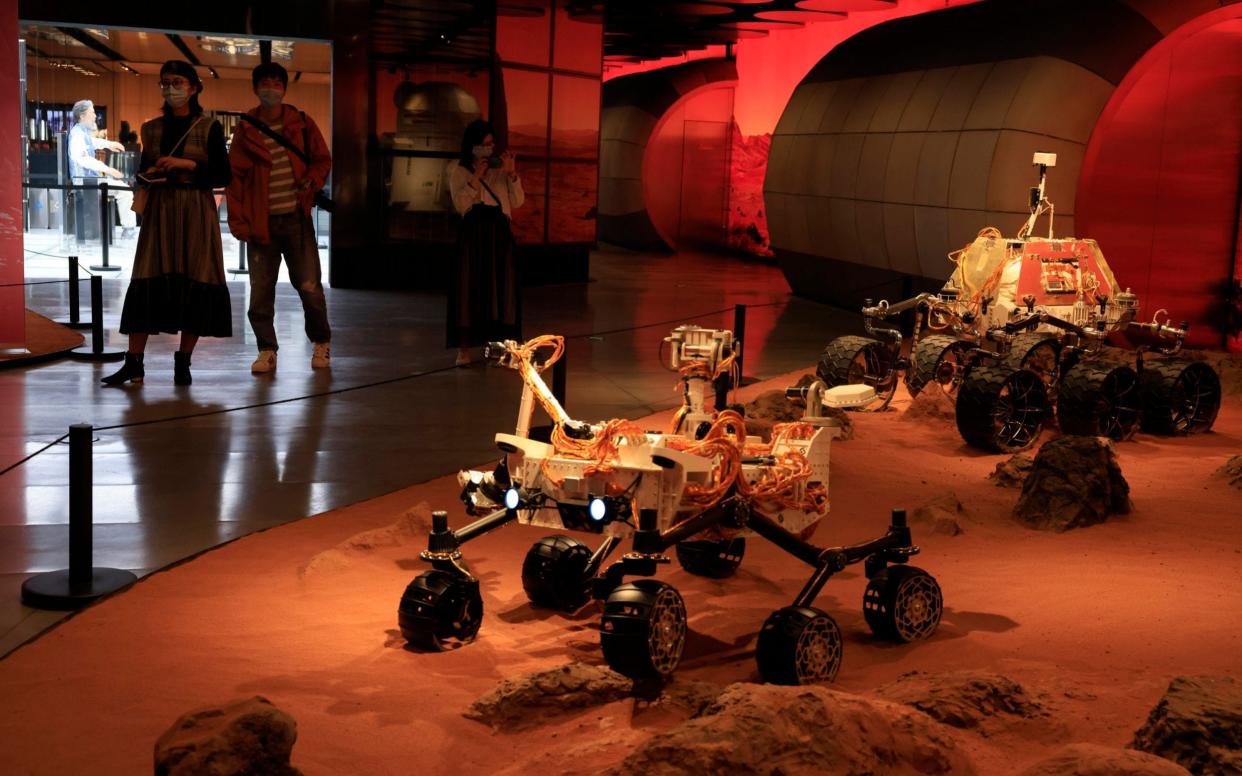 Visitors admire an exhibition depicting rovers on Mars in Beijing - AP Photo/Ng Han Guan