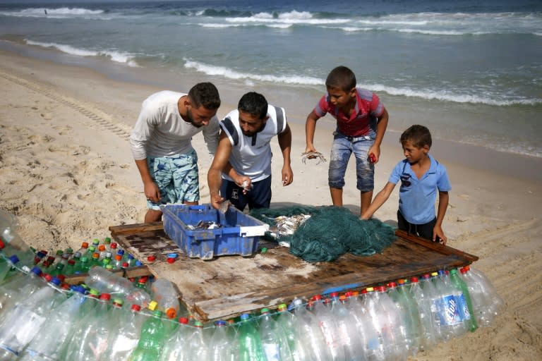 Palestinian fisherman Mouad Abu Zeid (2nd L) displays his catch after a fishing excursion on his boat, made of 700 Plastic empty bottles, on a beach in Rafah in the southern Gaza Strip on August 15, 2018