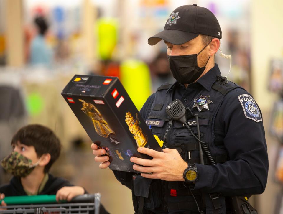 Eugene police Officer Adam Fischer reads the label on a gift selection to make sure it is age-appropriate during the annual Shop with a Cop with 9-year-old Jeremiah Clay, left.