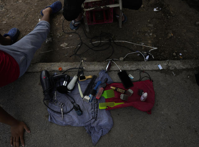A Venezuelan migrant waits to cut the hair of other fellow migrants, on the banks of the Rio Grande in Matamoros, Mexico, Sunday, May 14, 2023. As the U.S. ended its pandemic-era immigration restrictions, migrants are adapting to new asylum rules and legal pathways meant to discourage illegal crossings. (AP Photo/Fernando Llano)