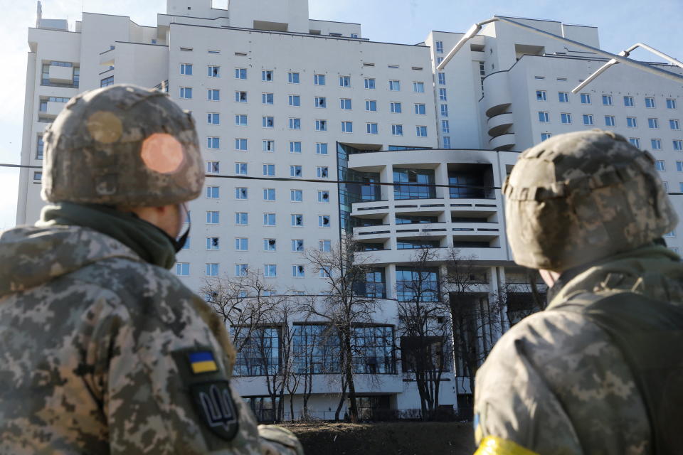 Ukrainian servicemen look at a damaged residential building, after Russia launched a massive military operation against Ukraine, in Kyiv, Ukraine February 26, 2022. REUTERS/Valentyn Ogirenko