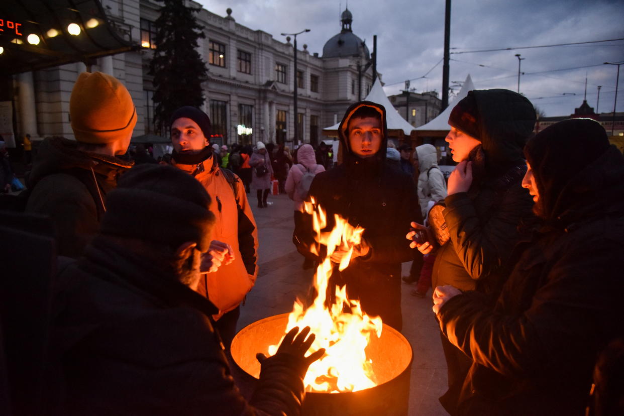 People fleeing Russia's invasion of Ukraine warm up by a fire barrel near the train station, in Lviv, Ukraine, on March 10. 