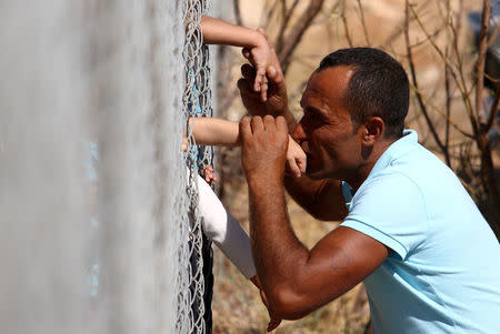 Ammar Hammasho from Syria who lives in Cyprus kisses his children who arrived at the refugee camp in Kokkinotrimithia outside Nicosia, Cyprus September 10, 2017. REUTERS/Yiannis Kourtoglou