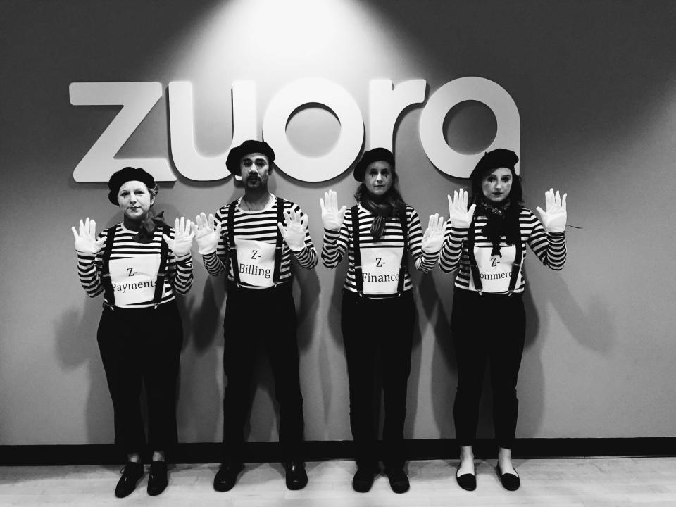 Four mimes standing in front of the Zuora logo.