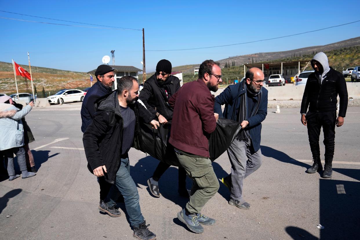 Men carry the dead body of a Syrian earthquake victim that will be transported to Syria for burial (AP)