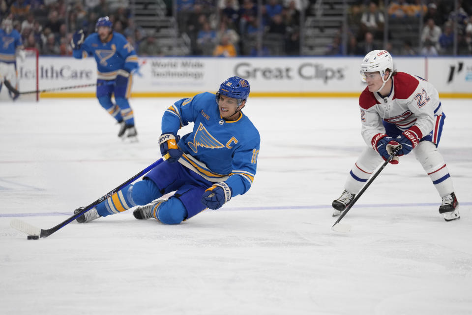 St. Louis Blues' Brayden Schenn (10) falls while bringing the puck down the ice as Montreal Canadiens' Cole Caufield (22) watches during the second period of an NHL hockey game Saturday, Nov. 4, 2023, in St. Louis. (AP Photo/Jeff Roberson)