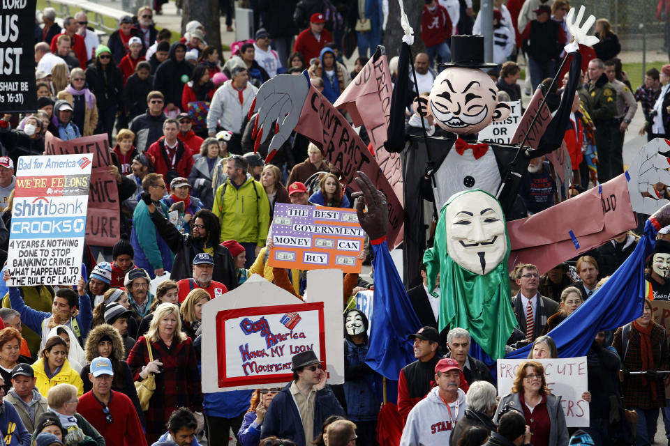 Protesters with the Occupy movement carry signs and characters to protest the foreclosure practices of banks including Wells Fargo after the conclusion of the 124th Rose Parade in Pasadena, Calif., Tuesday, Jan. 1, 2013. (AP Photo/Patrick T. Fallon)