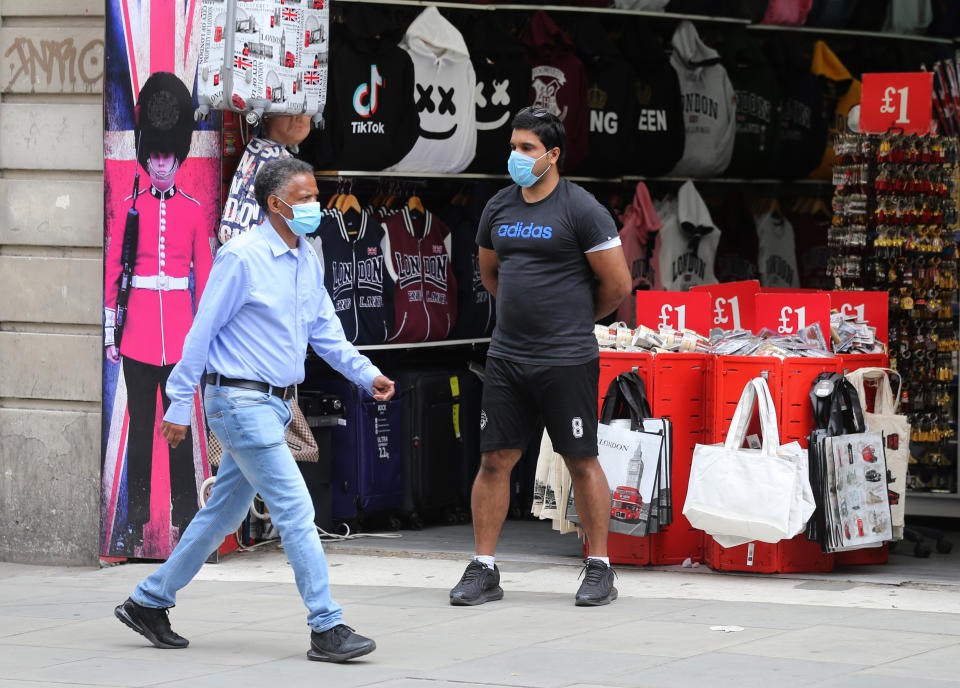 Shoppers wearing face masks walk past a souvenir store on Oxford Street, London