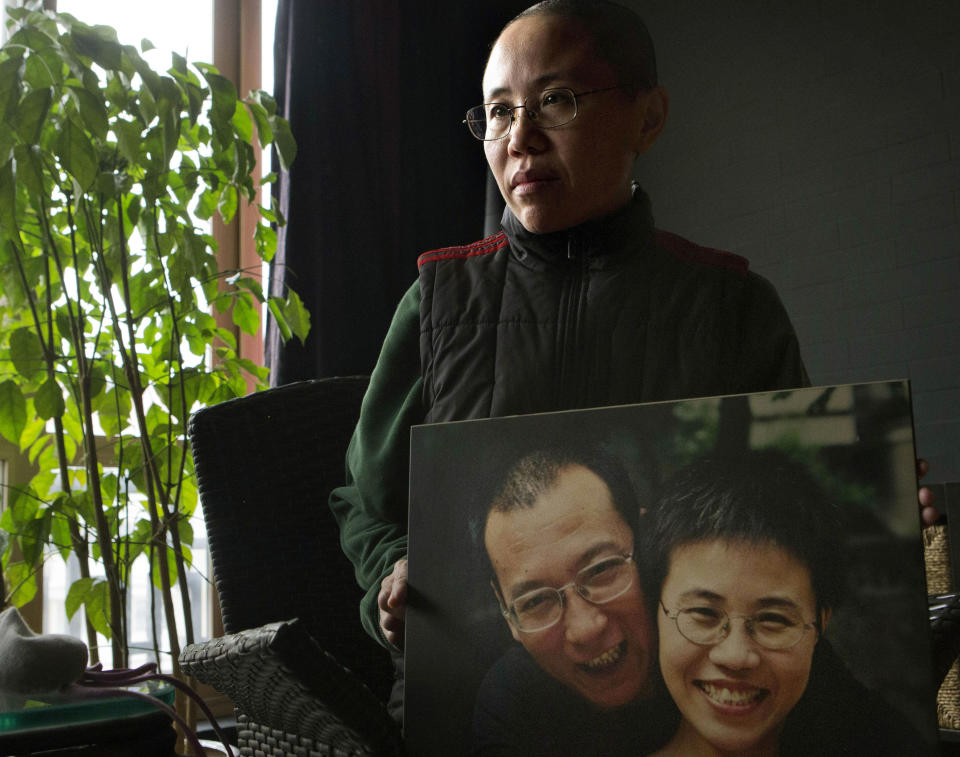 FILE - In this Dec. 6, 2012 file photo, Liu Xia, the wife of China's jailed Nobel Peace Prize laureate Liu Xiaobo, poses with a photo of her and her husband during an interview at her home in Beijing. The health of Liu Xia has deteriorated under lengthy house arrest and she urgently requires medical treatment, close friends said Friday, Feb. 14, 2014. (AP Photo/Ng Han Guan, File)