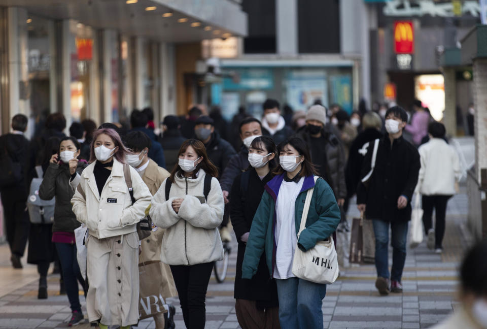 People wearing face masks walk by a train station during a coronavirus state of emergency in Tokyo on Thursday, Jan. 14, 2021. (AP Photo/Hiro Komae)