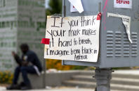 A sing posted on a street box by "Black Lives Matter" protesters, reads " If you think your mask makes it hard to breath, Imagine being black in America," seen at the Grand Park downtown Los Angeles, Thursday, June 18, 2020. California is now requiring people to wear masks in most indoor settings and outdoors when distancing isn't possible under a new statewide order. California Gov. Gavin Newsom previously allowed local governments to decide whether to mandate masks, and major counties like Los Angeles and San Francisco already require people to wear them inside and outside. (AP Photo/Damian Dovarganes)