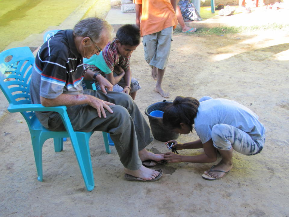 In this 2017 photo provided to The Associated Press, a young girl clips the toenails of now-defrocked Catholic priest Richard Daschbach at the Topu Honis children's shelter in Kutet, East Timor. Marco Sprizzi, Vatican ambassador to East Timor, stressed that Daschbach should not be allowed to be among children, but once Daschbach was expelled in 2018, the church could do little. (AP Photo)