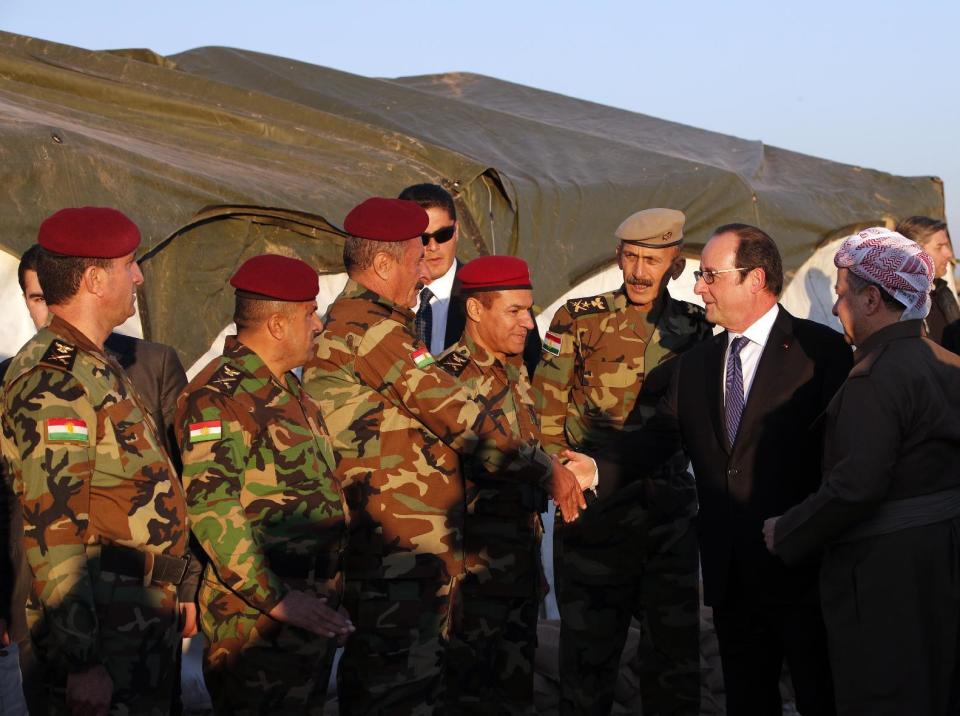 President of the Iraqi self-ruled Kurdish region, Massoud Barzani, right, introduces French President Francois Hollande to Kurdish Peshmerga soldiers as they visit a military outpost on the outskirts of the Islamic State-held city of Mosul, outside the Kurdish city of Irbil, Iraq, Monday, Jan. 2, 2017. Hollande is in Iraq for a one-day visit.(AP Photo/ Christophe Ena, Pool)