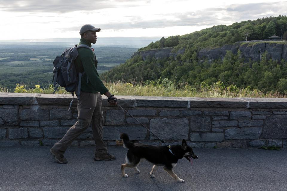 Hiking is one of the most popular activities for travelers visiting Alaska in June.
pictured: a Black man and his dog exploring inland Alaska