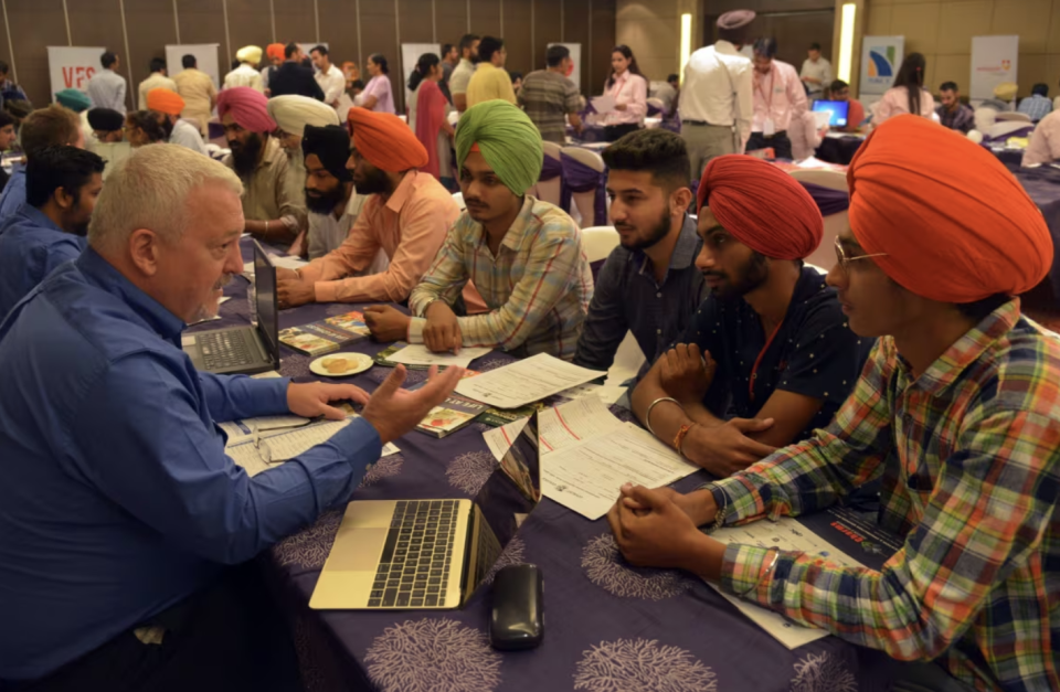 Indian students listen to Jim Whiteway, left, dean of the school of international business at Loyalist College in Belleville, Ont., at a Canadian education fair in Amritsar, India, on Sept. 16, 2015. Some 550 students attended the event showcasing 32 Canadian colleges and universities. (Narinder Nanu/AFP/Getty Images)