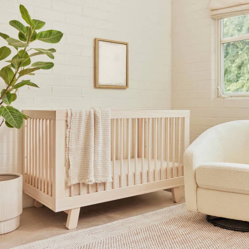 Light natural wood crib with thick angled legs in neutral nursery
