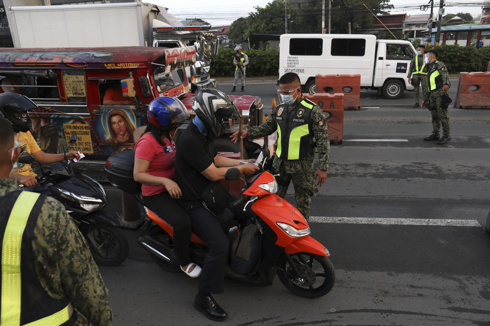 Police officers inspect motorists at a checkpoint during a stricter lockdown as a precaution against the spread of coronavirus on the outskirts of Marikina City, Philippines on Friday, August 6, 2021. Thousands of people jammed coronavirus vaccination centers in the Philippine capital, defying social distancing restrictions, after false news spread that unvaccinated residents would be deprived of cash aid or barred from leaving home during a two-week lockdown that started Friday. (AP Photo/Basilio Sepe)