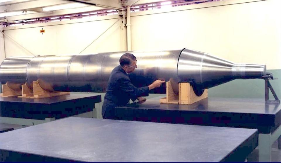 A man points to a model of the Manned Orbiting Laboratory.