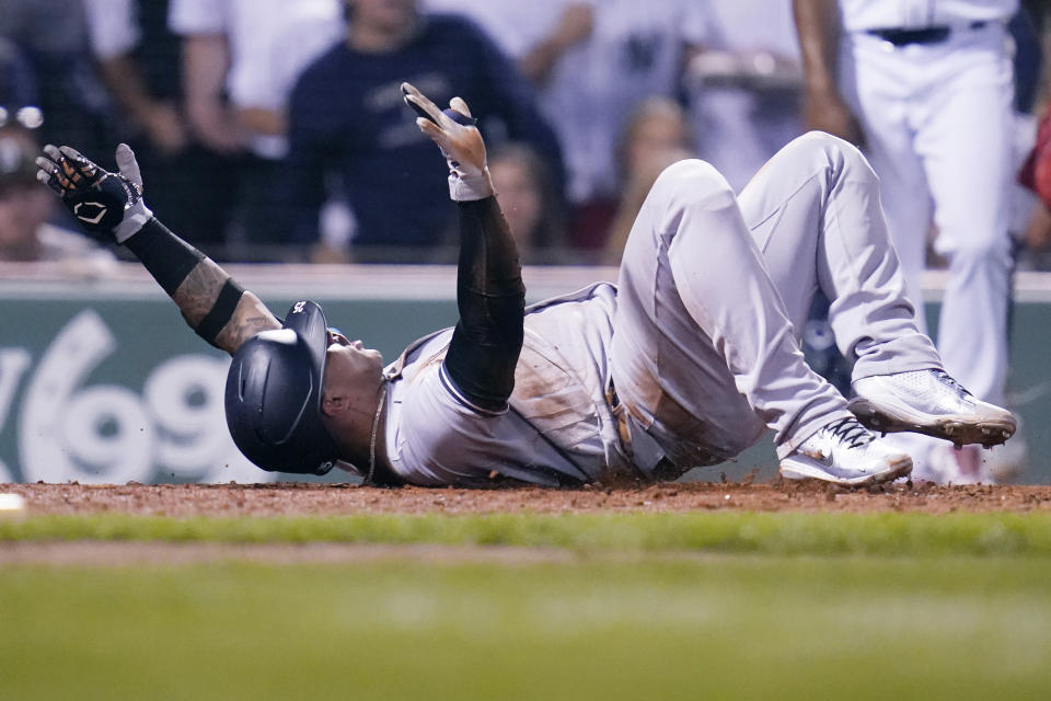 New York Yankees' Gleyber Torres celebrates after sliding home safely on a throwing error by Boston Red Sox catcher Connor Wong, after driving in Aaron Judge and Aaron Hicks on a single, during the fifth inning of a baseball game at Fenway Park, Wednesday, Sept. 14, 2022, in Boston. (AP Photo/Charles Krupa)