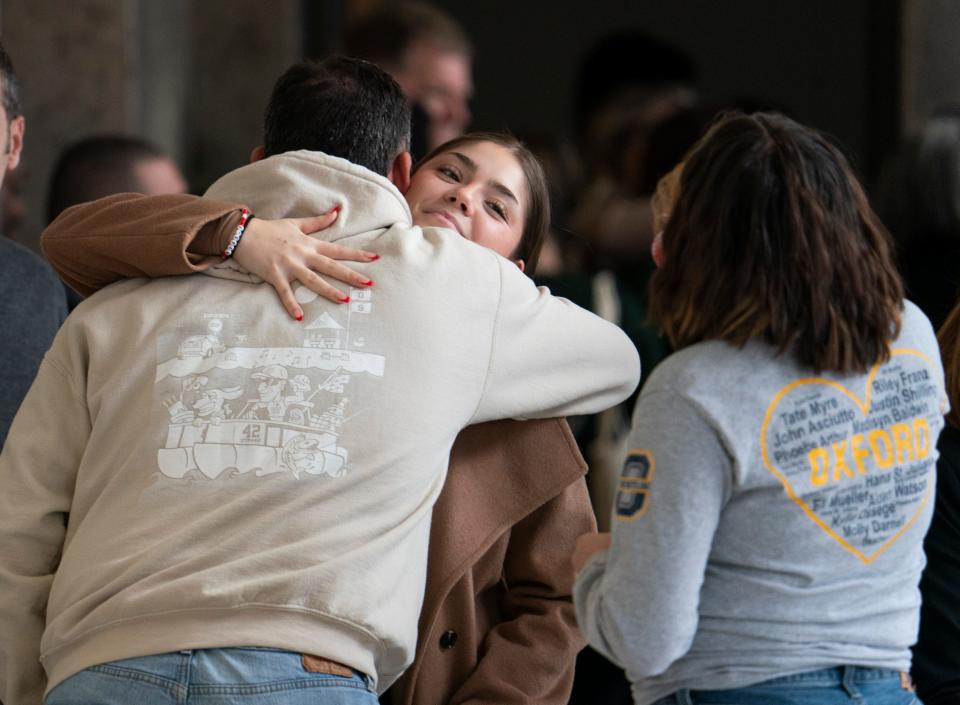 Buck Myre, (back to camera) father of Tate Myre who was killed in the Oxford High School shooting, hugs Olivia Guy who is wearing a bracelet that spells 'Justin' in the hallway during a break from the courtroom of Judge Kwame Rowe as Ethan Crumbley, the shooter is set to be sentenced at the Oakland County Courthouse Friday, Dec. 08, 2023.