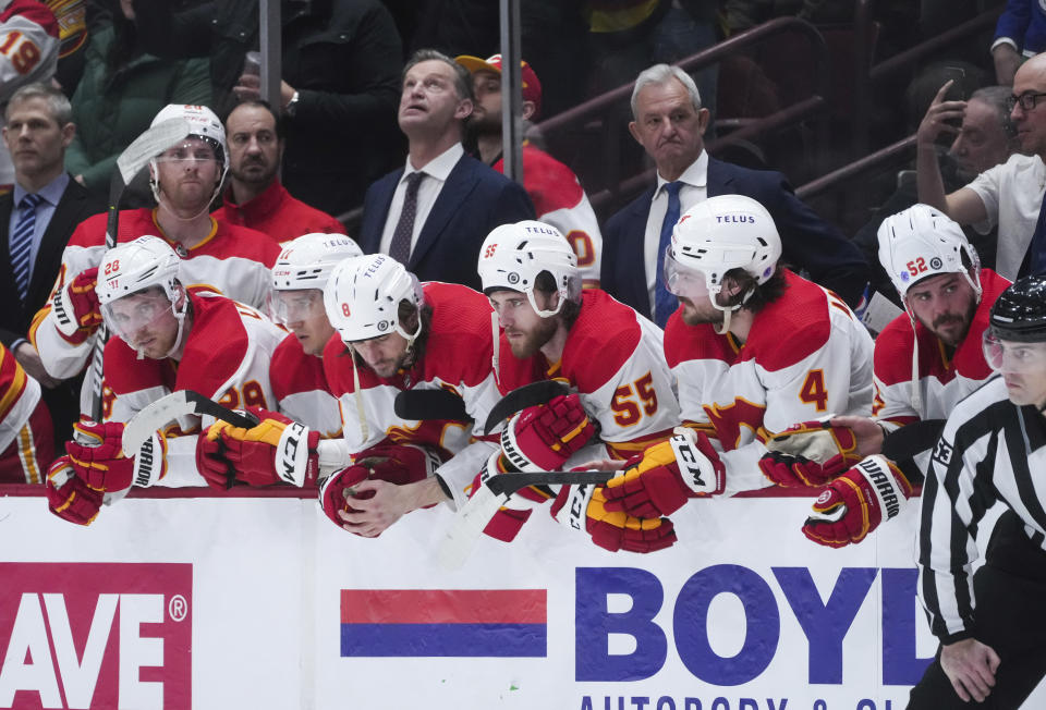 Calgary Flames' Christopher Tanev (8), Noah Hanifin (55) and MacKenzie Weegar (52) wear their helmets backward before Tyler Toffoli took the team's final shot and failed to score against the Vancouver Canucks in an NHL hockey game Saturday, April 8, 2023, in Vancouver, British Columbia. (Darryl Dyck/The Canadian Press via AP)