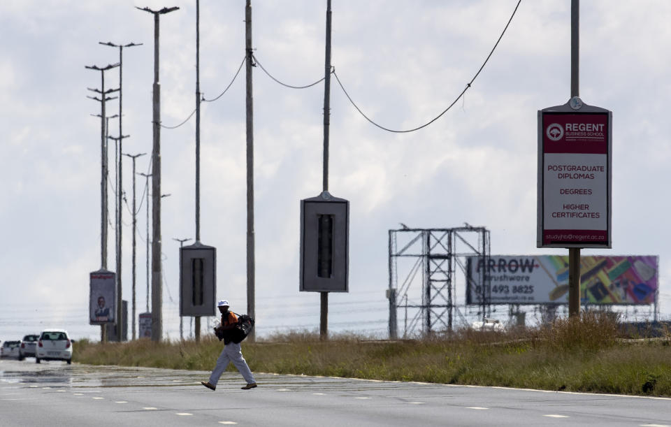 A man crosses on M2, a major highway on foot, in Johannesburg, South Africa, Friday, March 27, 2020. South Africa went into a nationwide lockdown for 21 days in an effort to mitigate the spread to the coronavirus. The new coronavirus causes mild or moderate symptoms for most people, but for some, especially older adults and people with existing health problems, it can cause more severe illness or death. (AP Photo/Themba Hadebe)