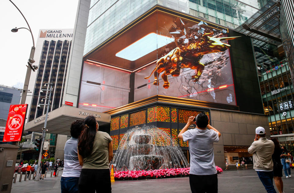 KUALA LUMPUR, MALAYSIA - 2021/02/10: People taking photos of the 3D hologram projection of the golden ox at Pavilion shopping mall. Chinese around the world will be celebrating the Chinese Lunar New Year and welcome the year of Ox which falls 12th on February. (Photo by Wong Fok Loy/SOPA Images/LightRocket via Getty Images)