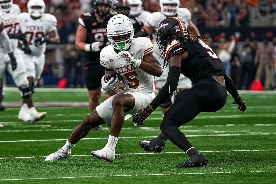Texas wide receiver Adonai Mitchell braces for a hit from Oklahoma State safety Kendal Daniels during Saturday's Big 12 Championship Game win in Arlington. The Longhorns, hoping to secure a College Football Playoff invitation on Sunday, have won their last two games by 57-7 and 49-21 scores.
