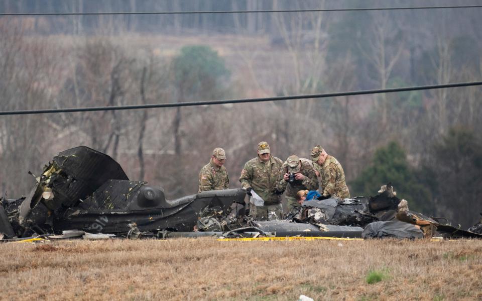 Military personnel and investigators search through debris from a Tennessee National Guard Black Hawk helicopter crash that killed two crew members along State Route 53 near Burwell Rd. Thursday, Feb. 16, 2023 in Harvest, Ala.