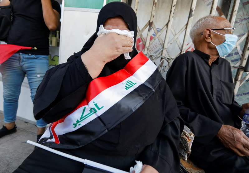 A woman with Iraqi flag, reacts during a protest over corruption, lack of jobs, and poor services, in Baghdad