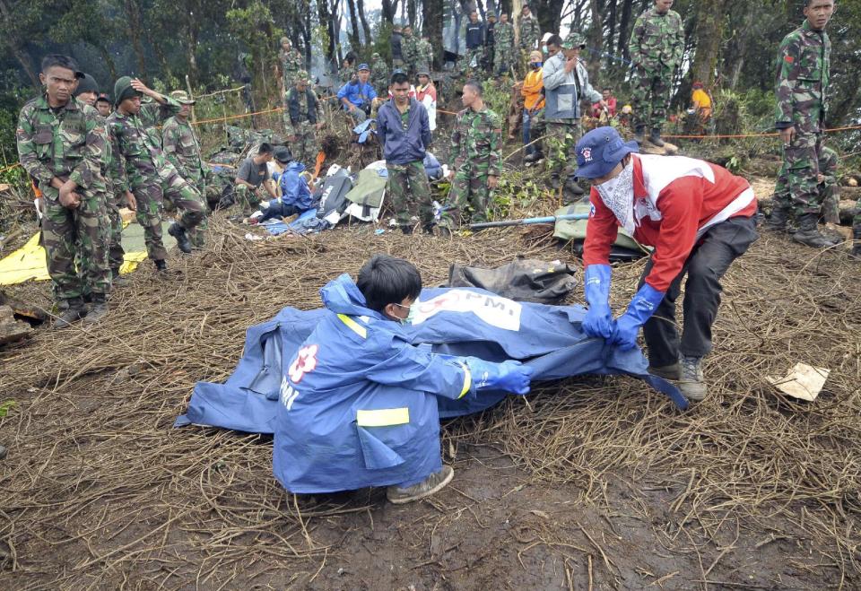 Rescuers prepare a body bag containing the remains of a victim of the crash of Sukhoi Superjet-100 on the peak of Mount Salak, West Java, Indonesia, Tuesday, May 15, 2012. Joint teams of Indonesian and Russian experts continued to comb through debris at the bottom of a 1,500-foot (500-meter) ravine on Tuesday afternoon to find the black box of the new passenger jet with 45 people on board that slammed into a cliff atop the dormant Indonesian volcano last week. (AP Photo/Jefri Tarigan)