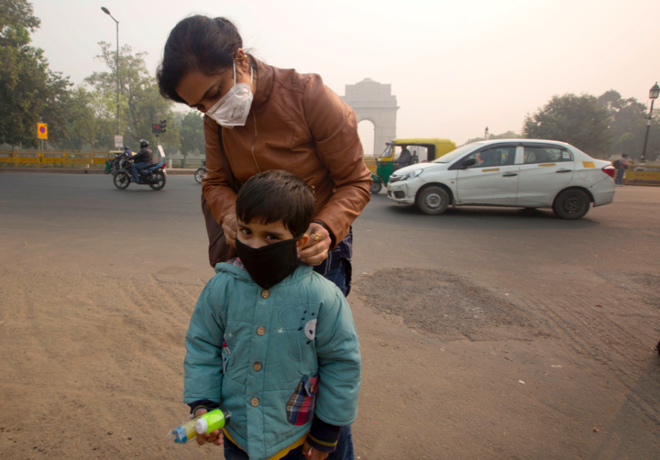 <em>An Indian mother puts a mask to her son a day after Diwali festival in New Delhi (AP)</em>