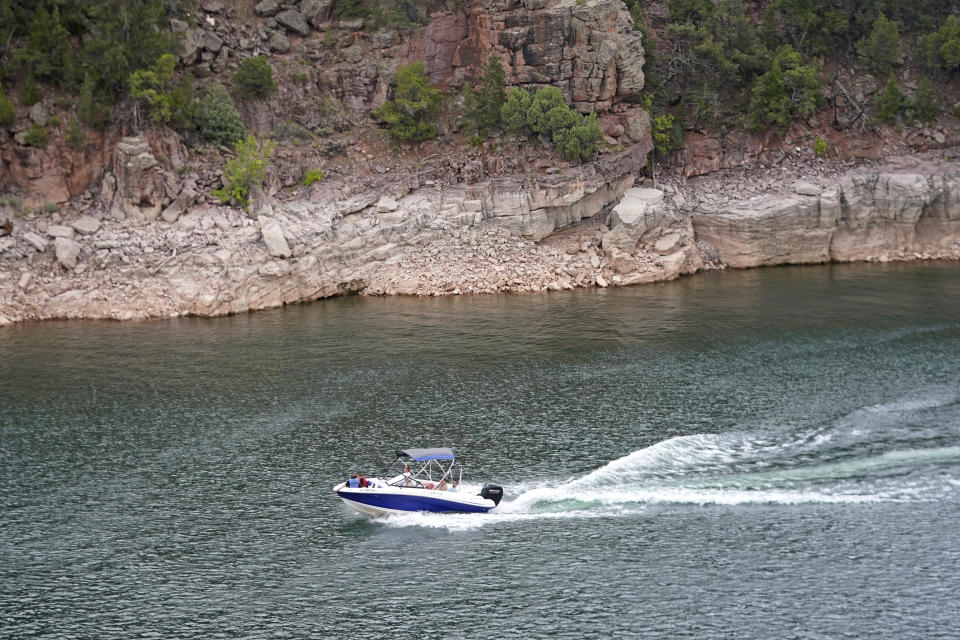 Boaters move along Flaming Gorge Reservoir, Friday, Aug. 5, 2022, in the northeastern corner of Utah. A boating and fishing paradise on the Utah-Wyoming line, Flaming Gorge is beginning to feel the effects of the two-decade megadrought gripping the southwestern U.S. (AP Photo/Rick Bowmer)