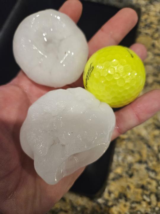 In this image provided by Randy Smith, a large chunks of hail are compared to the size of a golf ball, Wednesday night, March 13, 2024, in Shawnee, Kan. Volatile weather was honing in on parts of Kansas and Missouri Wednesday night, with some storms bringing massive chunks of hail. (Randy Smith via AP)