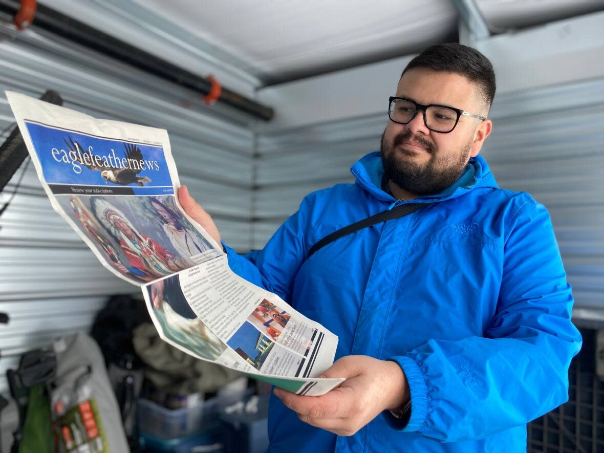 Eagle Feather News reporter Ben Borne shows off the last edition of the paper that was printed before the paper went on a hiatus, announced Monday. Editor-in-chief Kerry Benjoe says its ad revenue has been devastated and the paper can't afford to operate. (Travis Reddaway/CBC - image credit)