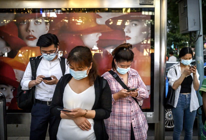 BEIJING, CHINA - SEPTEMBER 21: Chinese commuters look at their mobile phones as they wait at a bus stop on September 21, 2020 in Beijing, China. A U.S. federal judge has issued an injunction against President Donald Trump's executive order to ban the popular Chinese mobile app We Chat from U.S. app stores as of midnight on Sunday. The action is seen as an escalation between the two countries regarding tech issues and the order would also prevent U.S. companies from processing transactions made via the app. (Photo by Kevin Frayer/Getty Images)