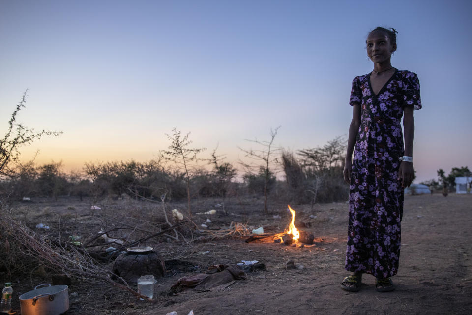 Una joven tigray, que huyó del conflicto en la región etíope de Tigray, mira a mujeres que cocinan delante de su refugio en el campo de refugiados Umm Rakouba, en Qadarif, en el este de Sudán, el 25 de noviembre de 2020. (AP Foto/Nariman El-Mofty)